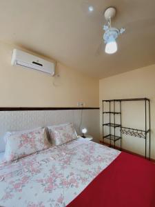 伦索伊斯Pousada da Villa的一间卧室配有一张带红色毯子的床和风扇。