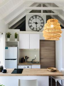 Oyster PondSTUDIO COSY LES FRANGIPANNIERS的厨房配有桌子和墙上的时钟