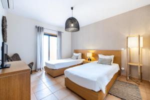 卢斯Aum Praia da Luz Resort Apartment的一间酒店客房,设有两张床和电视