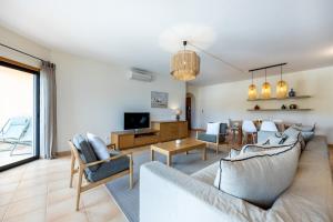 卢斯Aum Praia da Luz Resort Apartment的客厅配有沙发、椅子和电视