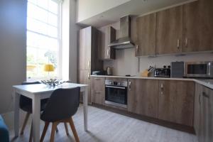 奇切斯特Beautiful flat in luxury Graylingwell development的厨房配有木制橱柜、桌子和桌椅