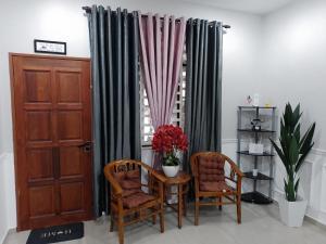 克提Homestay Qaseh Kerteh的客房设有桌子、两把椅子和窗户。
