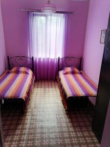 加格拉Дом под ключ的紫色客房,窗户前设有两张床