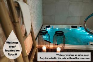 圣地亚哥－德孔波斯特拉Via Aetcal Hotel & Wellness的浴室内装有2把蜡烛的浴缸