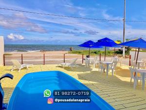 圣若泽-达科罗阿格兰迪Pousada Lá Na Praia的海滩旁的游泳池,配有椅子和遮阳伞
