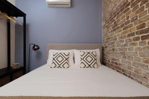 科孚镇Spianada Collection of Studios & Apartments by Konnect的砖墙旁的一张带白色床单和枕头的床