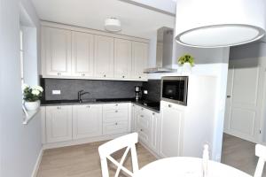 青斯特KranichSuite - Zingst的厨房配有白色橱柜、水槽和桌子