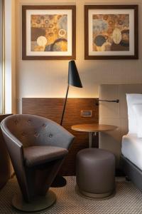 日内瓦日内瓦皇冠假日酒店的配有床、椅子和桌子的酒店客房