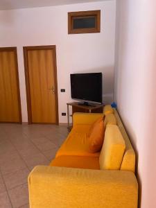 帕尔蒂尼科Holiday mode EVA的客厅设有一张黄色沙发,配有电视