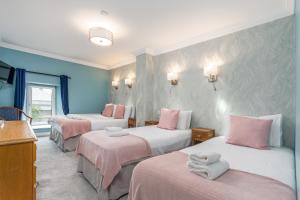 基尔肯尼Troysgate House的一间设有三张床、粉色和白色床单的客房