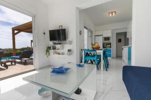 拉卡尼亚White Blue Villa的厨房以及带玻璃桌的起居室。