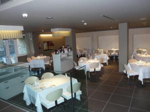 奥尔迪诺布林格别墅温泉酒店的餐厅配有白色的桌椅和瓶装葡萄酒