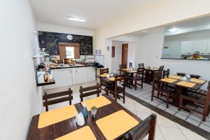 纳塔尔Pousada Terra do Sol Natal的一间带木桌椅的餐厅和一间厨房