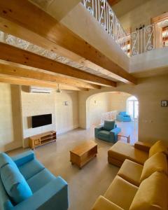 萨奈特Ta' Giga Farmhouse的大型客厅设有蓝色的沙发和电视。