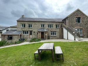 JacobstowTHE OLD RECTORY SOUTHCOTT APARTMENT in Jacobstow 10 mins to Widemouth bay and Crackington Haven,15 mins Bude,20 mins tintagel, 27 mins Port Issac的石头房子前面设有野餐桌