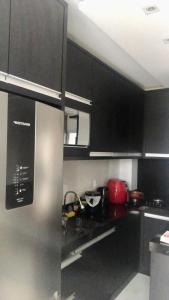 帕苏迪托雷斯brisas da maré的厨房配有黑色橱柜和不锈钢冰箱
