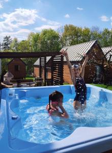 桑多梅日Lawendowo- sauna jacuzzi domki w ogrodzie i apartamenty w kamienicy的两个孩子在游泳池玩耍