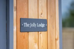 莱姆里吉斯The Jolly Lodge-Sea Views-Free Parking的木门上读着欢乐小屋的标志