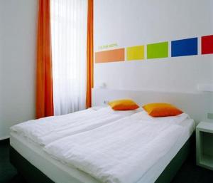 美因河畔法兰克福彩色酒店的一张带两个橙色枕头的白色床