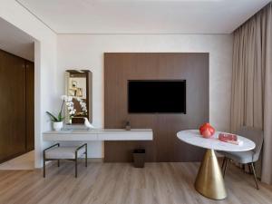 迪拜Movenpick Jumeirah Village Triangle的客厅配有电视和桌子