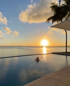 坎昆Casa Tortugas Boutique Hotel - CANCUN Hidden Gem的在游泳池里的人,在海洋中欣赏日落