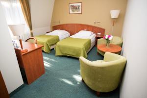 波兹南Hotel Rezydencja Solei的酒店客房,配有两张床和椅子