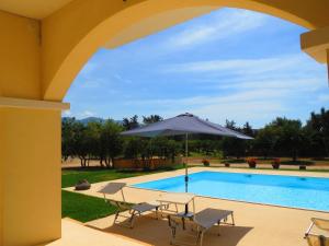 Sant' IsidoroVilla Bulcrini的一个带桌子和遮阳伞的庭院,毗邻一个游泳池
