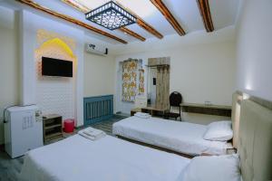 布哈拉BUKHARA HOUSE hotel的酒店客房设有两张床和电视。