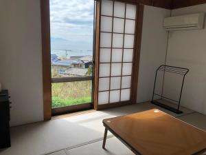 KasaokaShiraishi Island International Villa的客房设有桌子和大窗户。