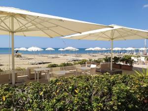 卡斯蒂里昂纳·德拉佩米拉马雷酒店的海滩上设有桌子和遮阳伞,还有大海