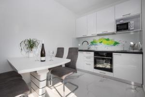 波斯蒂拉Apartments BlueView的白色的厨房配有白色的桌子和椅子