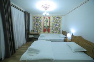 布哈拉Bukhara Baraka Boutique Hotel的一间卧室设有两张床,墙上挂着一幅画