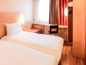 里尔宜必思加雷斯里尔中心酒店的一间酒店客房,配有一张白色的床和一张书桌