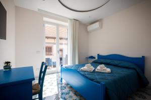 PianilloPalazzo San Giovanni - near Path of the Gods的一间卧室配有蓝色的床、一张桌子和一个窗户。