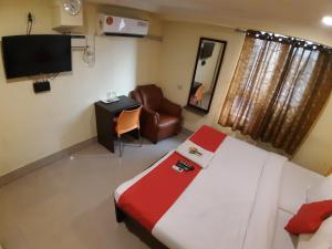 钦奈Hotel Akash inn的一间卧室配有一张床、一把椅子和电视