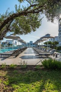 科斯镇钻石豪华酒店－仅限成年人的游泳池旁的一排椅子和遮阳伞