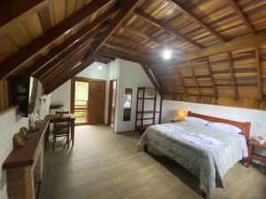 蒙特韦尔迪Pousada Recanto do Sauá - Monte Verde的一间卧室配有一张床铺和一张桌子,还设有一间厨房