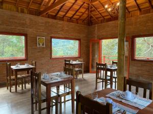 蒙特韦尔迪Pousada Recanto do Sauá - Monte Verde的用餐室设有桌椅和窗户。