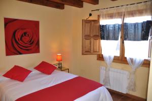 Horcajo de la SierraEl Rincón de la Trilla - El Linar的卧室配有一张床,墙上挂着红玫瑰