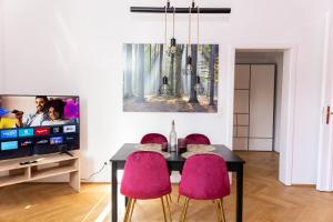 维也纳Schönbrunn Serenity Luxurious Ruby Apartment with Palace Views的一间带桌子和两把粉红色椅子的用餐室