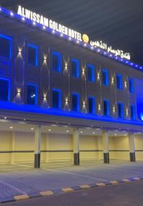 Al Ḩanākīyahفندق الوسام الذهبي的建筑的侧面有蓝色的灯光