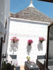 阿尔贝罗贝洛"B&B La Lanterna" Trulli & Dimore Storiche的白色墙壁上种有盆栽植物的庭院