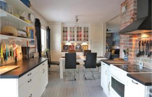 克里斯蒂安斯塔德Beautiful Home In Kristianstad With Wifi的厨房配有白色橱柜和一张带黑色椅子的桌子。