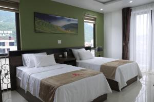 河江Phúc Lâm Hotel的配有两张床铺的绿色墙壁和窗户