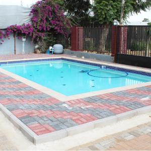 哈博罗内Platinum Hotel的一座大型游泳池,设有砖地板和砖砌的四柱形墙