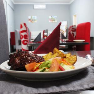 哈博罗内Platinum Hotel的桌上一盘带肉和蔬菜的食物