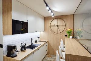 卡尔帕奇Kamilkowy Apartament的厨房配有白色橱柜、水槽和时钟
