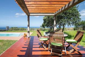 大里贝拉Country House in Azores - S. Miguel的庭院内带椅子和桌子的木制凉亭