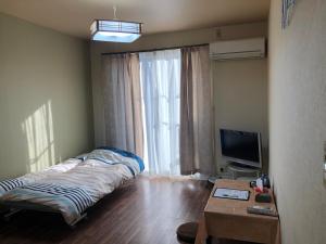 熊本アルピエa敷地内無料駐車場付き的一间卧室配有一张床、一台电视和一张桌子
