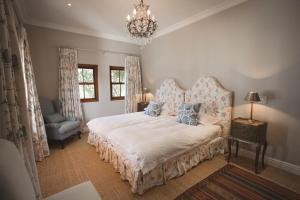 普利登堡湾Lombard Villa的一间卧室配有一张床、一把椅子和一个吊灯。